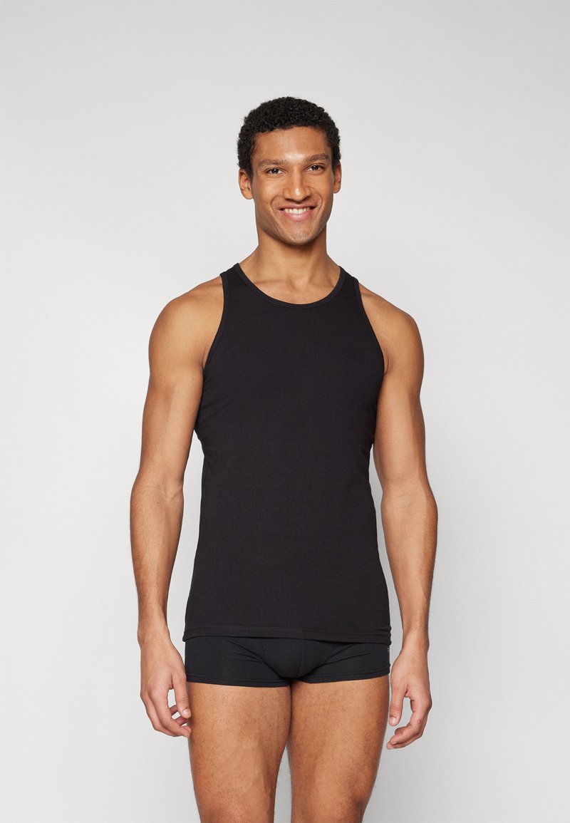 Czarny top na ramionczkach wykonany z bawełny, z okrągłym dekoltem i bezrękawowym fasonem. Noszony z dopasowanymi czarnymi majtkami.