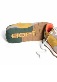Sneaker met een gele leren bovenkant, grijze suède accenten, oranje kraag en een gemarmerde rubberen zool in bruin en groen met de tekst "HOFF."