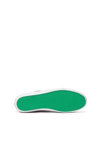 Vita sneakers liggande på sidan som visar en grön texturerad gummisula mot en vit bakgrund.