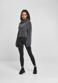Tumehall cropped turtleneck sviiter, millel on tekstuuriline viimistlus, koos mustade legginsitega, millel on külgdetailid. Mustad spordišed sisaldavad.