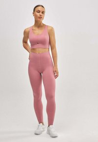 Conjunto de sujetador deportivo y leggings rosas en una tela suave y elástica. Los leggings tienen un diseño de cintura alta y acentos sin costuras.