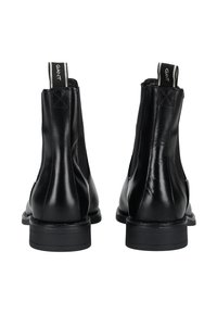 Stivaletti neri in pelle con pannelli elastici laterali, punta arrotondata e suola piatta. Presenta un'etichetta con "GANT" sul retro.