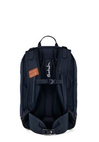 Sac à dos noir avec des bretelles rembourrées, une poignée supérieure et un accent en cuir brun. Comprend une boucle de poitrine ajustable et un doublure en mesh.