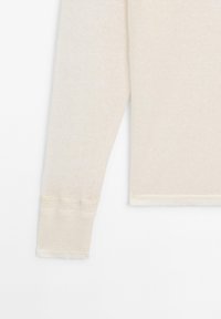 Pull beige à manches longues en maille avec poignets et ourlet côtelés, présenté sur un fond blanc.