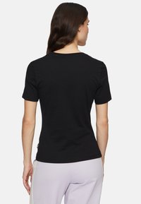 T-shirt en coton noir à manches courtes et col rond classique ; texture lisse et design ajusté, présenté de dos.
