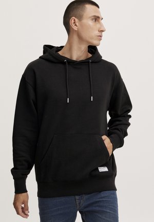 Sudadera negra con capucha, hecha de una tela suave. Presenta un bolsillo tipo canguro, cordones ajustables y puños acanalados en el dobladillo.