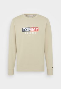 Felpa beige in cotone, con polsini e orlo a costine. Grafica frontale con la scritta "TOMMY JEANS" in rosso, blu navy e bianco.