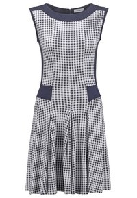 Robe sans manches à carreaux noirs et blancs avec des accents bleu marine sur l'encolure, les côtés et les poches, dotée d'une jupe évasée et d'une fermeture éclair au dos.