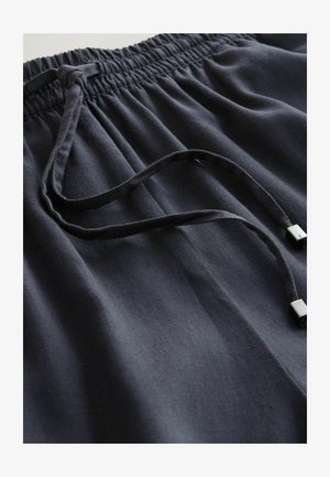 Mørkeblå shorts med elastisk talje, lavet af blødt stof, med snøre med metalender og subtile folder i materialet.