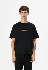 T-shirt nera a maniche corte in cotone con scollo rotondo, caratterizzata da un logo rosso e bianco sul davanti e una vestibilità comoda.