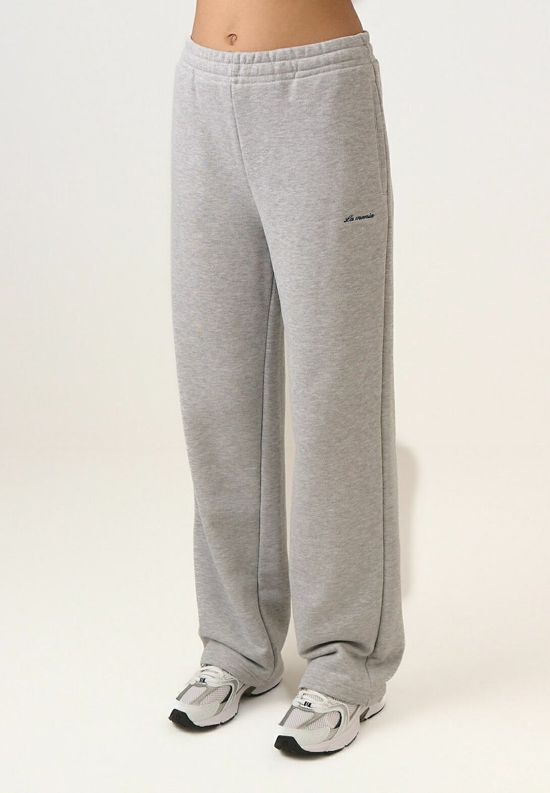 Pantaloni de trening gri realizați dintr-un material moale, cu croială lejeră, talie elastică și un mic logo de accent în albastru închis la șold.