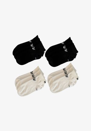 Two pairs of black and two pairs of white ankle socks with Puma logo and size 35 displayed on a white background.