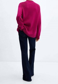 Fuchsia knit sweater with a round neckline, ribbed cuffs, and hem paired with dark denim flared jeans. Back view showing relaxed fit.