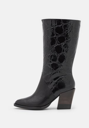 Botte noire mi-mollet avec un bout pointu, un talon bloc et un motif crocodile brillant texturé sur la partie supérieure.