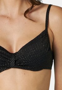 Top bikini nero con tessuto testurizzato e punti oro, forma triangolare, dettaglio attorcigliato nella parte anteriore e spalline regolabili.