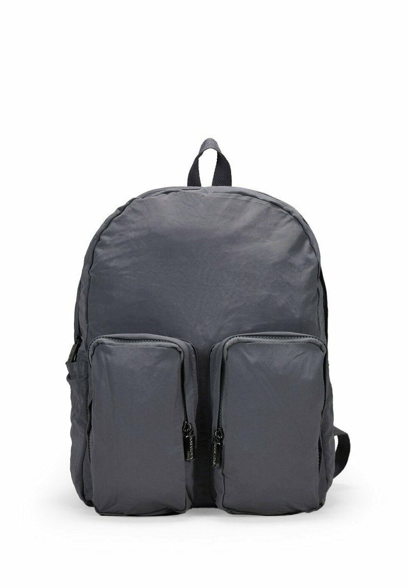 Mochila de tela gris con forma redondeada, dos bolsillos frontales con cremallera y un asa en la parte superior. Superficie ligeramente texturizada. Correas ajustables.