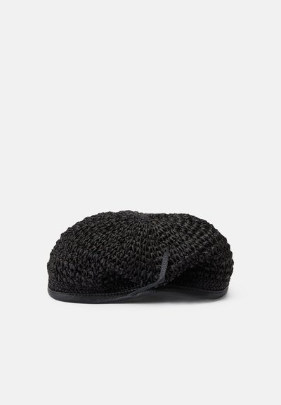Sac plat tissé noir en forme arrondie, avec une surface texturée et une sangle fine. Le matériau semble léger et flexible.