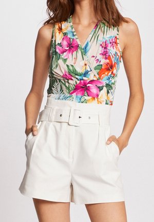 Body floral avec un design croisé mettant en valeur des motifs vibrants de rose, orange et vert. Associé à un short blanc taille haute avec une ceinture.