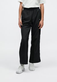 Μαύρο παντελόνι φόρμας από ελαφρύ ύφασμα, με ελαστική μέση, ίσια μπατζάκια και εμφανές λογότυπο στη αριστερή πλευρά.