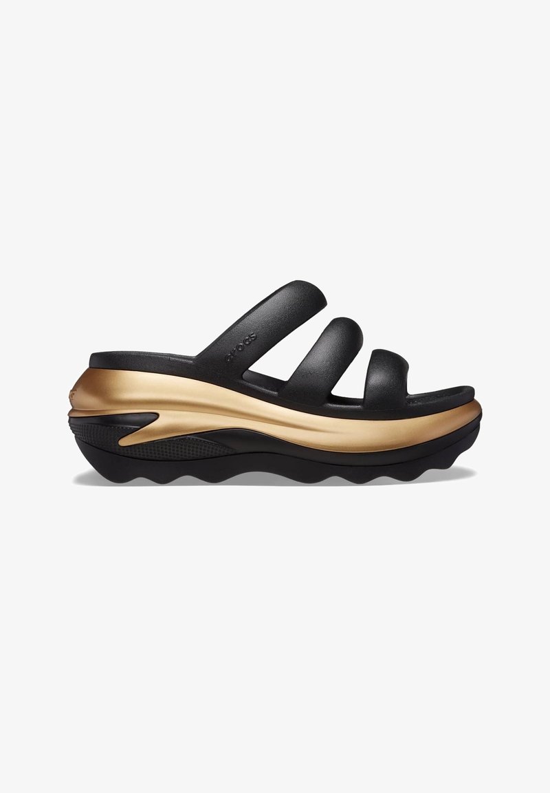 Sandale slide noire avec trois larges brides et une épaisse semelle ondulée dorée et noire, conçue pour le confort et un usage décontracté.