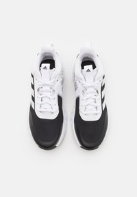 Chaussures de sport noir et blanc avec une tige en mesh, des panneaux texturés, trois accents de rayures noires et une semelle rembourrée.