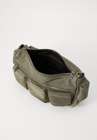 Sac à main en nylon vert olive avec plusieurs compartiments zippés, texture lisse et accents en métal argenté. Le dessus ouvert révèle un intérieur spacieux.