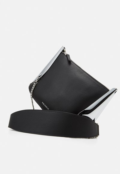 Sort læderhåndtaske med en skinnende sølvlås, lynlåslukning og justerbar rem. Har en glat tekstur og minimalistisk design.
