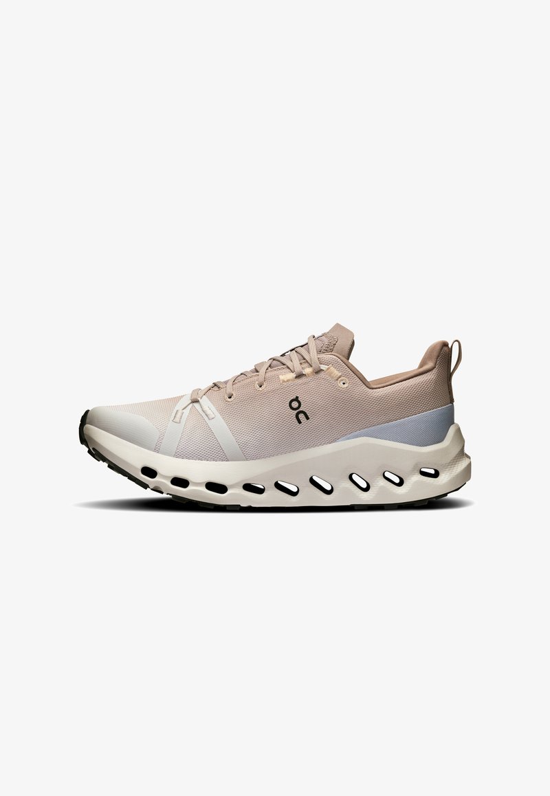 Beige hardloopschoen met een ademend bovenwerk van mesh, contrasterende grijze accenten en een gevoerde zool met meerdere afvoeropeningen.