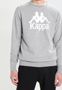Grå sweatshirt lavet af bomuldsblanding. Har en stor hvid Kappa-logo og grafik. Ribstrikkede manchetter og kant, rund halsudskæring.