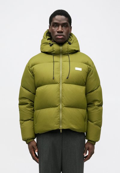 Giacca a vento verde con cappuccio, dotata di chiusura con zip, cordini regolabili e una toppa logo sul davanti. Texture morbida e design trapuntato.