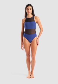 Costume da bagno intero blu con un pannello nero trasparente in vita, collo alto e design aderente. Tessuto morbido e elasticizzato.