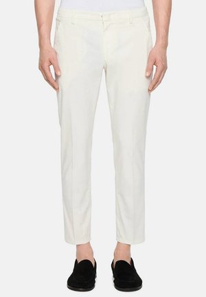 Pantaloni di cotone bianchi con una vestibilità slim, caratterizzati da una parte anteriore piatta e tasche laterali, abbinati a mocassini in suede neri. Texture liscia.