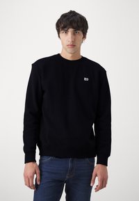 Sweatshirt noir en mélange de coton, avec un col rond, des poignets et un bas côtelés, et un petit logo brodé blanc sur la poitrine.