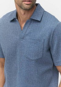 Kortärmad pikétröja i ett blått herringbone-mönster, med en mjuk textur, en liten bröstficka och en design med notch-krage.