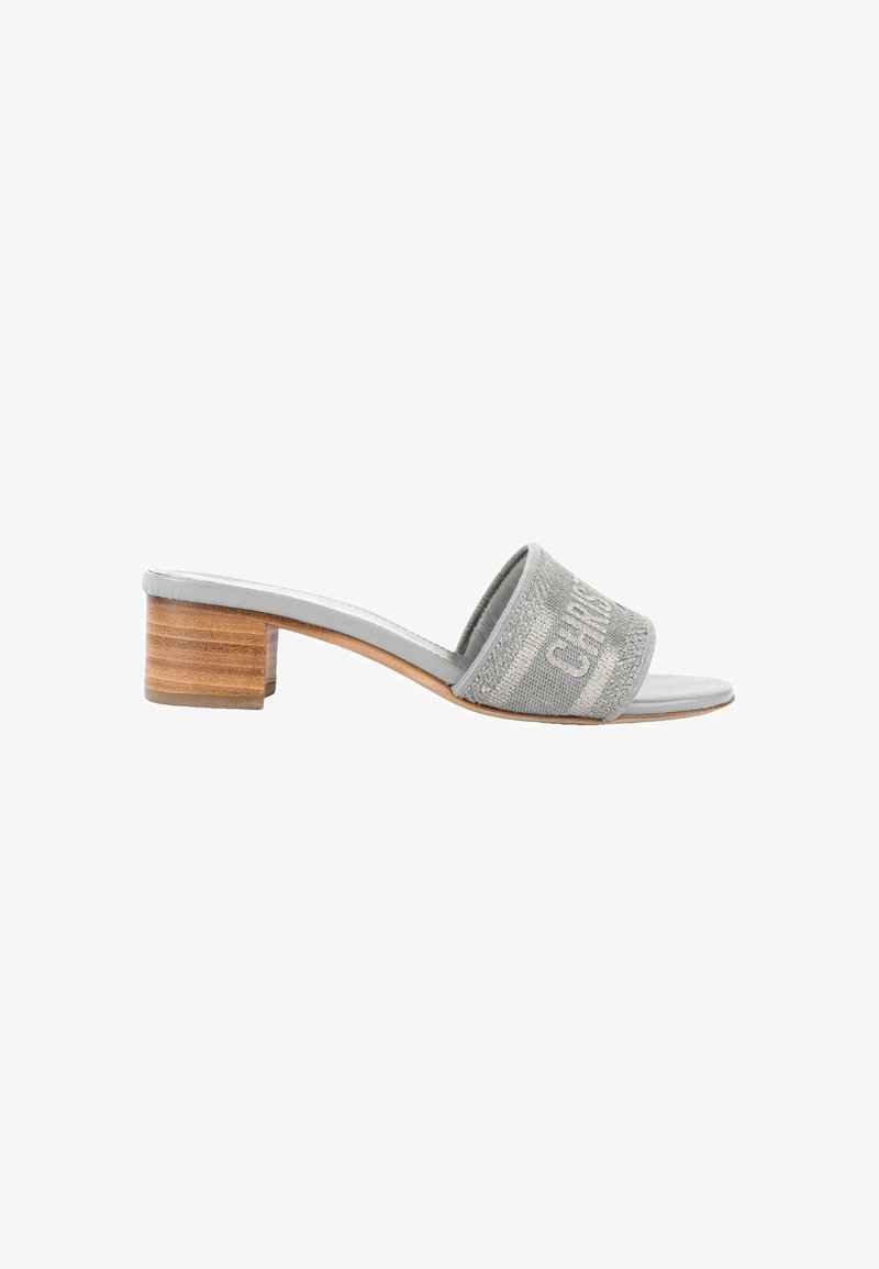 Sandale mule grise avec un petit talon en bois superposé et une large sangle en tissu brodée d’un logo de créateur.