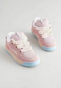 Różowe sneakersy z siateczkowych i zamszowych materiałów, z plecionymi beżowymi sznurówkami, niebieską podeszwą i białym wyściółką na kołnierzu.