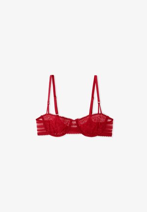 Soutien-gorge en dentelle rouge avec armatures et panneaux transparents, doté de bretelles réglables, de bords festonnés et de motifs floraux sur le tissu.