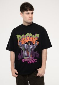 Black oversized T-shirt featuring a colorful graphic of a figure in a striped sweater with text "B.I.G." and "Brooklyn's Finest" in bold colors.
