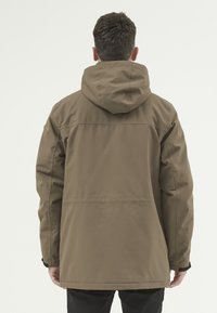 Brun huva jacka med rak skärning, textilerad tyg och elastiska muddar; har synlig sömnad längs ryggen.