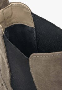 Szare zamszowe botki za kostkę z czarnym materiałowym wnętrzem i gładką skórzaną podszewką. Posiadają lekko teksturowaną powierzchnię i kontrastowe przeszycia.