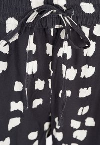 Shorts neri in tessuto con un motivo astratto bianco, una vita elastica con cordino e una texture morbida e leggera.