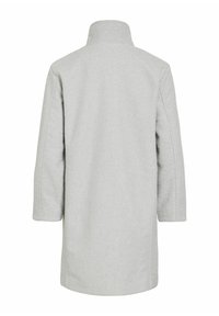 Gaiši pelēks, vidēja garuma mētelis ar augstu apkakli, izgatavots no teksturēta auduma. Raksturīgas nolaistas plecu līnijas un taisnas piedurknes. Nav redzama metāla detaļu.