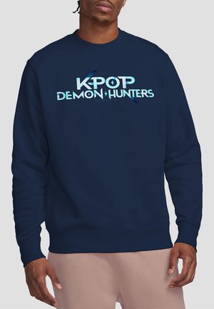 Dunkelblaues Sweatshirt aus Fleece mit einem auffälligen Grafikdruck, der den Text "KPOP DEMON HUNTERS" in hellblau und weißen Farben zeigt.