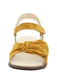 Yellow suede sandal with a knotted front design, adjustable ankle strap, and a cushioned insole. Flat sole with subtle texture.