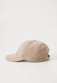 Beige corduroy-lippis, jossa on kaareva lippa, tekstuuri pinta ja hihnakiinnitys takana; sisältää kuusi ilmanvaihtoaukkoa.