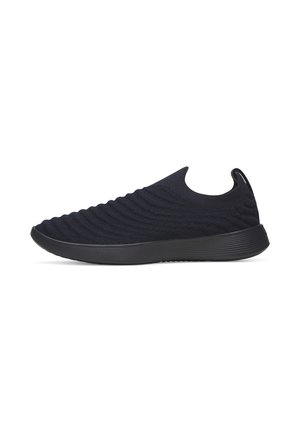 Baskets noires slip-on avec dessus en maille texturée et semelle en caoutchouc épaisse, vue latérale sur fond blanc.