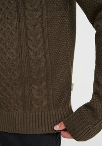 Dunkelbrauner Strickpullover mit strukturierten Mustern, gerippten Bündchen und Zopfmuster-Design, aus weichem, haptischem Stoff gefertigt.