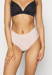 Hoge taille, beige bikini onderkant met een gladde textuur, naadloos ontwerp en een comfortabele pasvorm, gecombineerd met een zwarte, zachte driehoek beha.