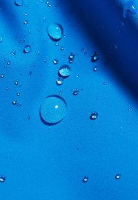 Tessuto blu impermeabile con goccioline d'acqua sulla sua superficie, che mette in evidenza una trama liscia e un colore solido e vibrante.