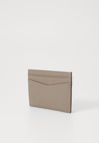 Läderkortshållare i ljus taupe med texturerad yta, fyra fack på ena sidan och en subtil diagonal detalj på toppen.